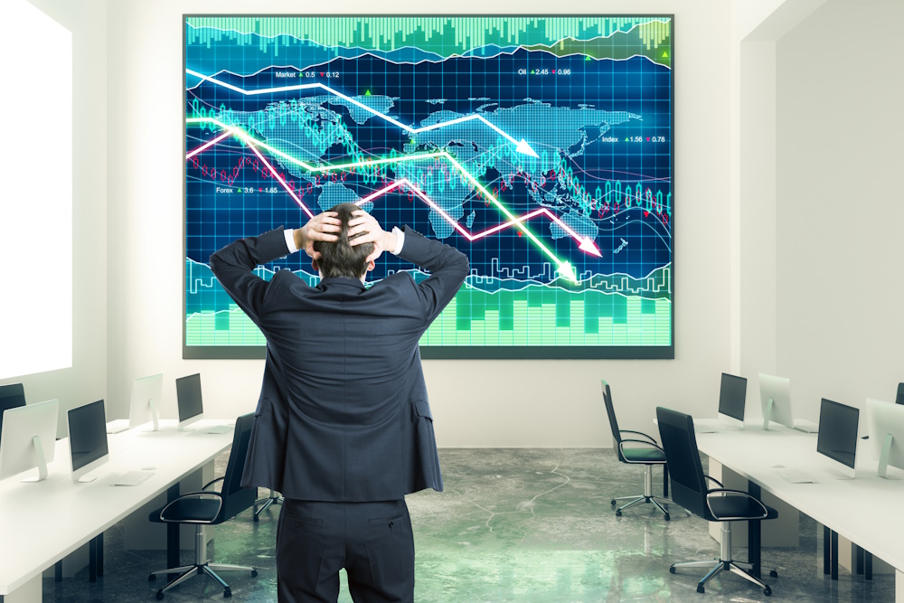 Businessman grabs the head in open space office with business chart at the wall